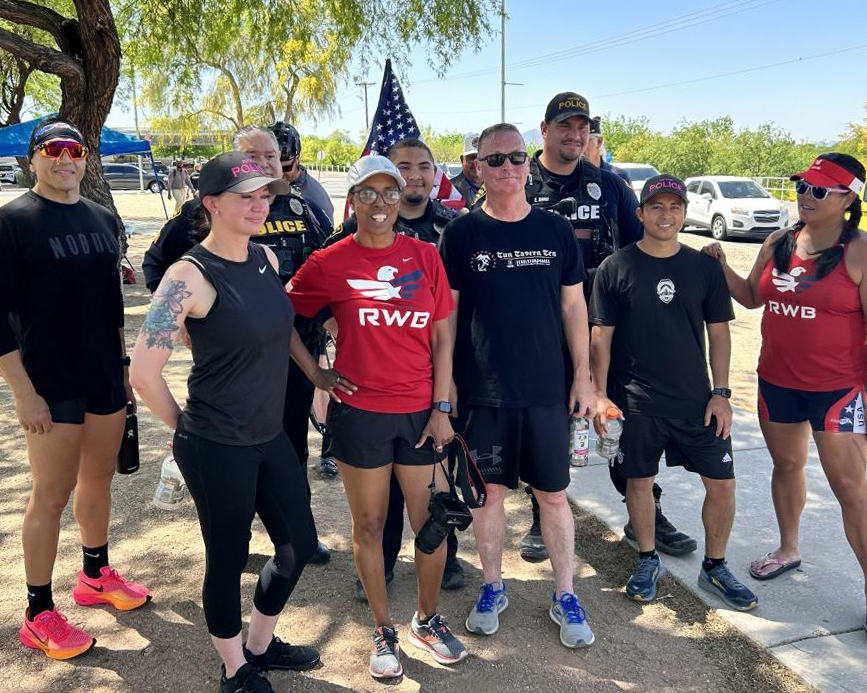 People outdoors, dressed for running, standing in front of an American flag