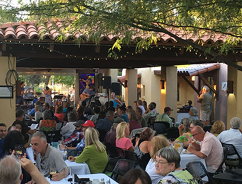 Picture of the event with many people sitting around tables listening to music