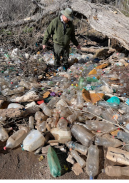 A man stands and surrounded by  the plastic bottles