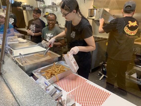 Workers inside of Just Churros serving food.