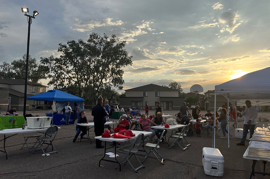 TPD ODS members and community members outside, at tables, the sun mostly behind a hill.