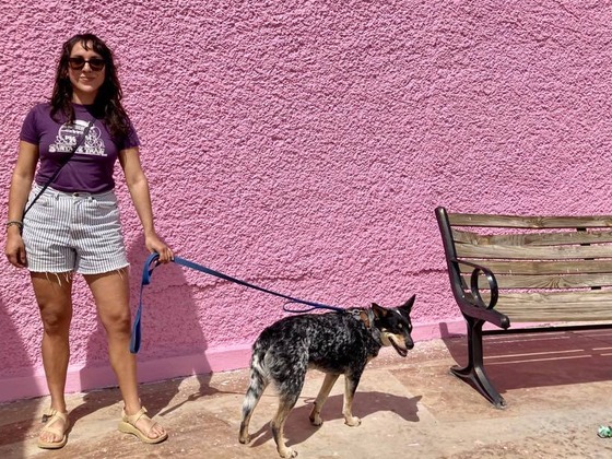 Photo of Gabriela Barillas and her dog in front of a pink wall.