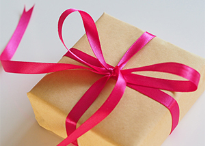 Gift package wrapped in brown paper and tied with a pink ribbon.