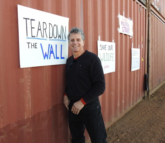 Image of Beau Phillips in front of the container border wall along the Arizona / Mexico border.