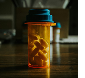 Partially empty pill bottle with a dark background.