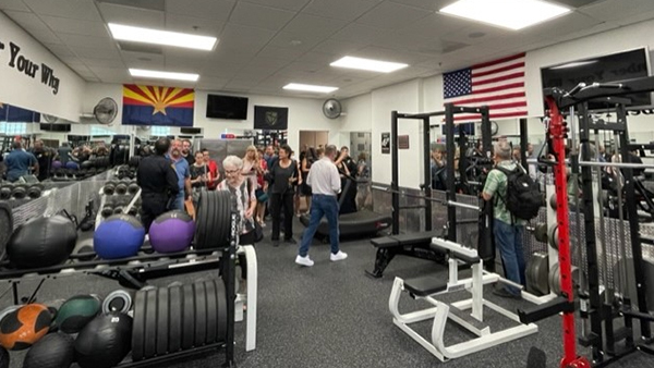 People touring a well-equipped and spacious gym.