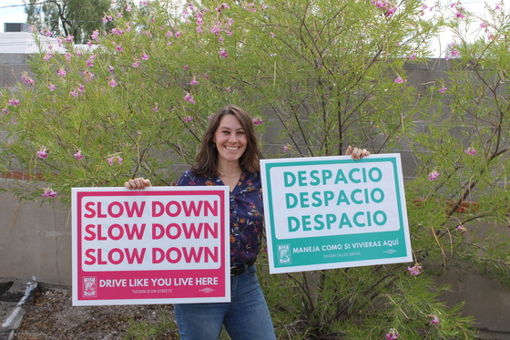 Photo of Ward 3 Council aid Shannon holding two "slow down" signs