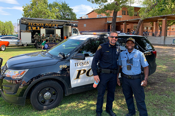 TPD Chief Kasmar and CSO Ames in front of a patrol vehicle outdoors at a school.