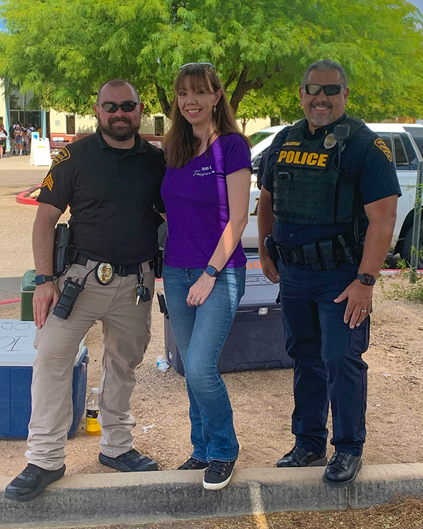 Ward 4 Council Member Lee outside at event with a uniformed TPD officer on either side.