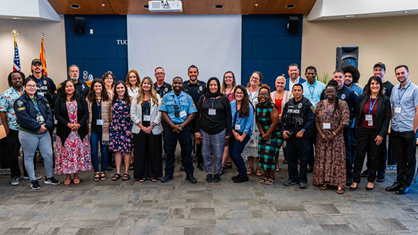 A large crowd lines up for a group photo in a meeting room. A mix of TPD members and community members, including from the refugee community.