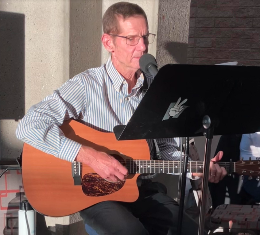 Picture of Steve K perform at the TROT fundraiser event with his guitar and wear blue long sleeve