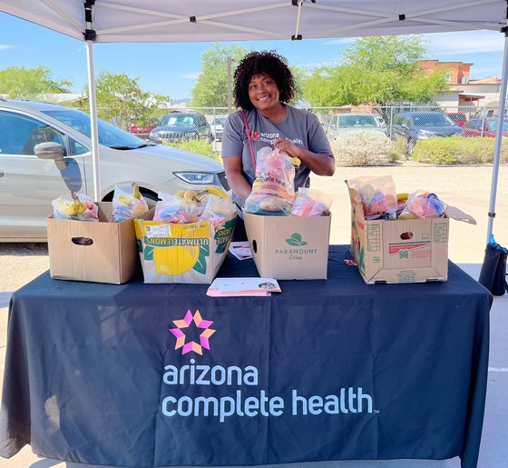 photo of Tina with Arizona Complete Health handing out fresh produce bags at the Amphi event.