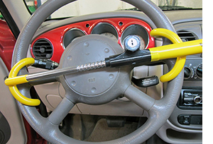 Yellow steering wheel lock on gray steering wheel.
