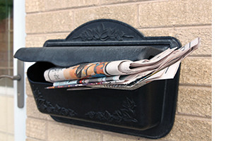 Black residential mailbox overflowing with mail