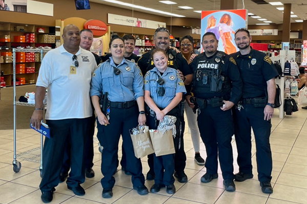 TPD Police Officers, Community Service Officers and community members pose for a group photo inside a retail store.