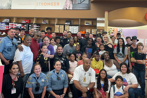 TPD uniformed personnel and community members pose for a group photo inside a retail store.