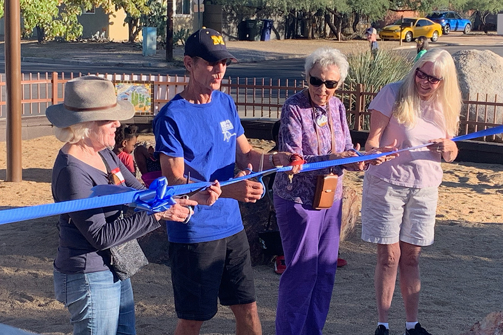 Council Member Steve Kozachik cuts a ribbon outdoors with community members.