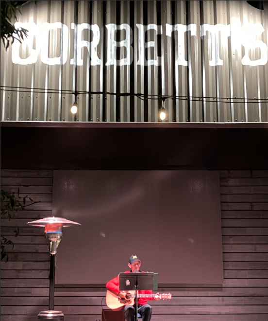 Steve K performs his music at Corbett and wears hat and red long sleeve