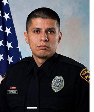Department photo of uniformed officer in front of an American flag.