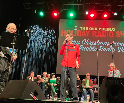Steve K is on stage at the Old Pueblo Holiday Radio Show with Dave Fitzsimmons stand next to him