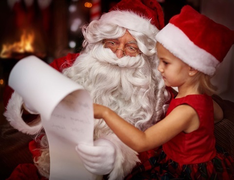 Photo of Santa reading to a girl.