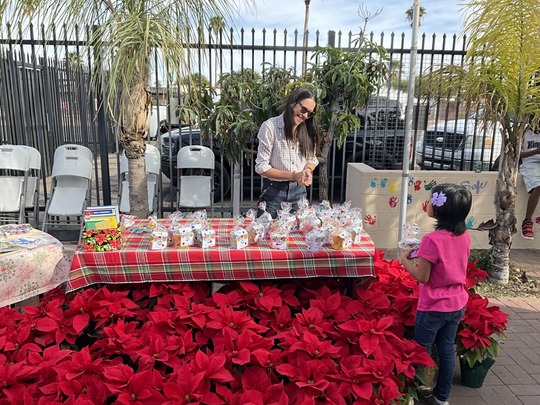 Photo of Marlene Avelino Handing out seeds and poinsettias at WIldcat Inn Holiday Party.