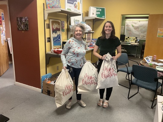 Photo of Erin Durband and shannon Jenkins with three bags of donated gifts for the Wildcat Inn. 