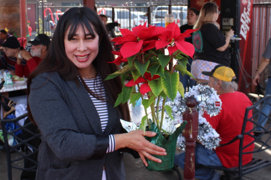 Photo a WIldcat Inn resident holding her new poinsettia.