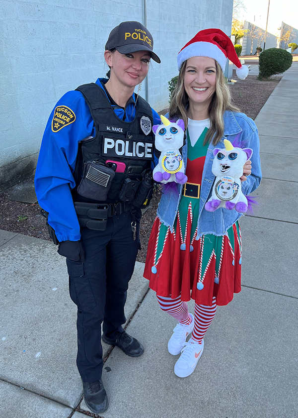 A uniformed TPD officer and a woman dressed as a Santa's helper stand outside.