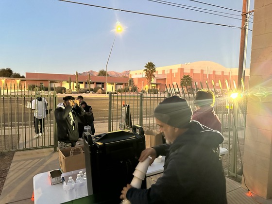 Photo of Shawn Milligan helping to serve hot chocolate to some unhoused residents early in the morning.