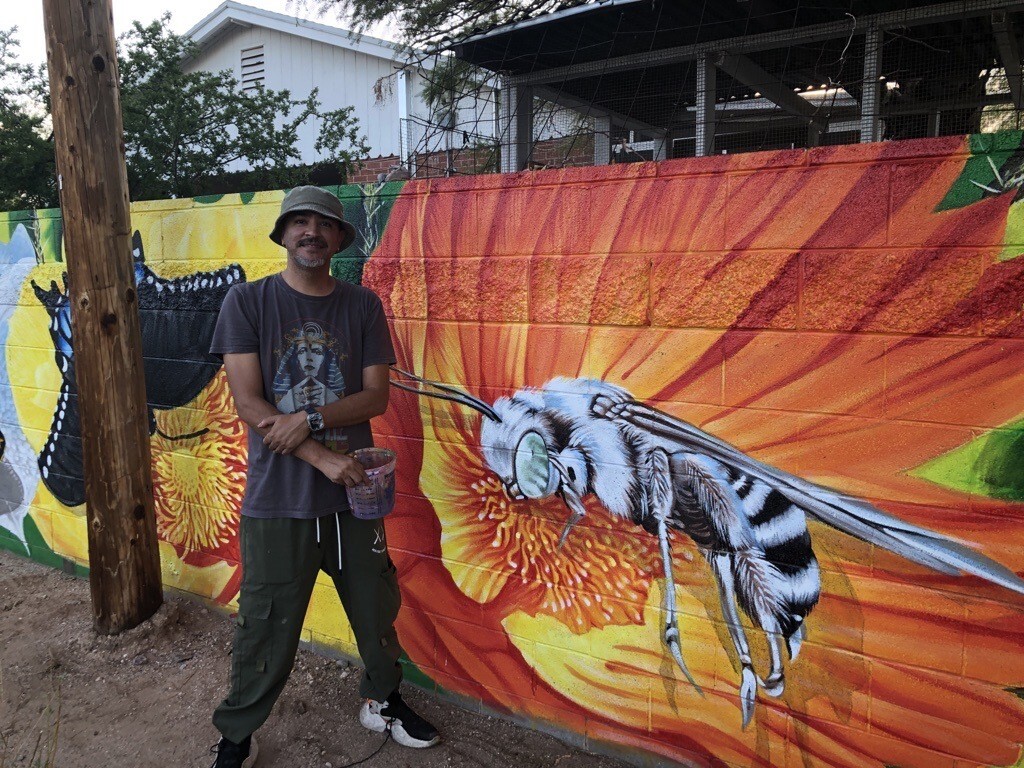 Photo of Ignacio Garcia in front of his mural Desert Pollinators
