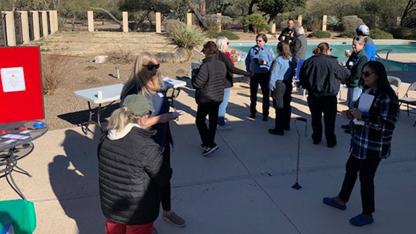Residents and TPD members stand outside by a pool enjoying coffee together