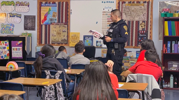 TPD officer in front of a white board in a classroom, teaching a class.
