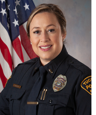 Department photo of smiling female TPD captain in uniform in front of an American flag.