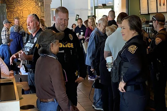 Crowded Starbuck's with officers and CSOs in uniform speaking with community members.
