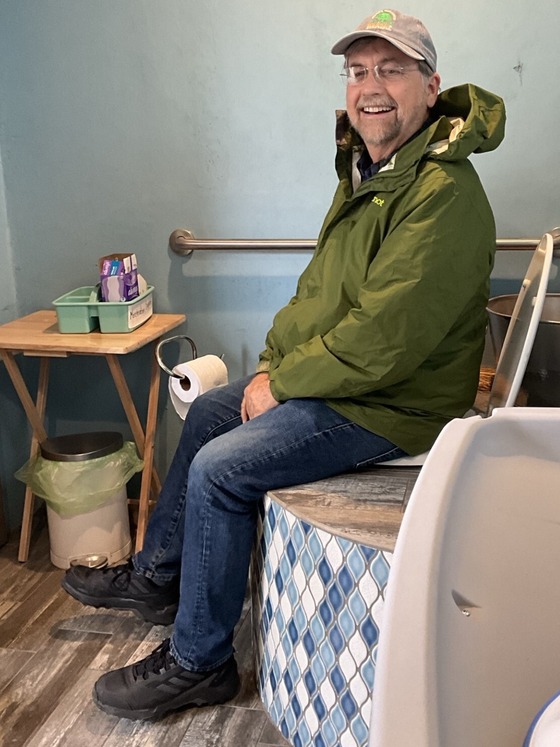 Photo of Vice Mayor Kevin Dahl sitting on a composting toilet.