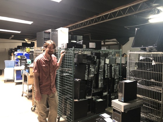 Photo of Coleman Hammer-Tomizuka the Director of Tech and E-recycle next to some refurbish equipment.