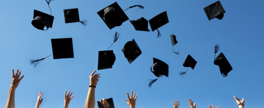 Photo of Graduation caps being thrown into the air.