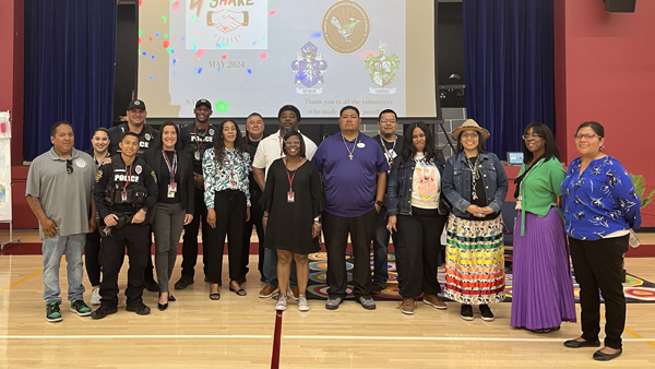 TPD members and community members stand for a group photo inside a school auditorium.