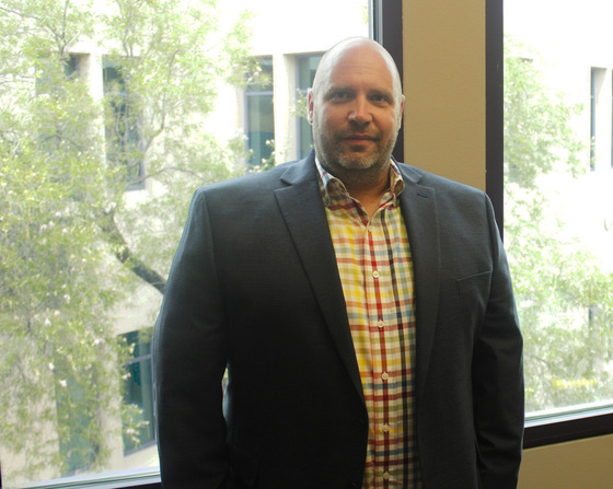 Photo of Jason Thorpe standing by his window in his office.