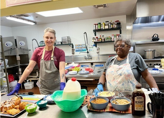 Photo of two long term volunteers offering breakfast options.