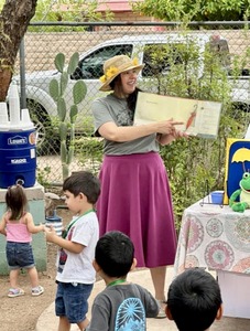 Image of a camp leader reading to the children