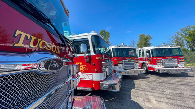 Four Tucson Fire Department trucks lined up in a parking lot