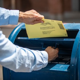 Photo of person putting ballot into mailbox
