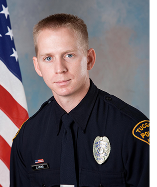 TPD officer in uniform in front of an American flag.