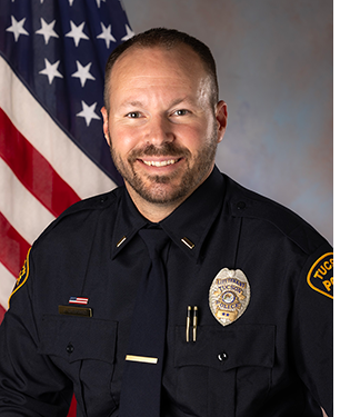 Department photo of TPD lieutenant in uniform in front of an American flag.