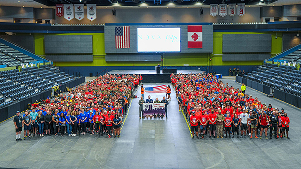 Group photo of Tower Challenge participants on the floor of the TCC showing the stairs in the stands that they will soon climb.