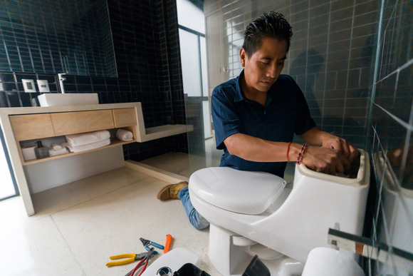 Man fixing flapper inside of toilet tank