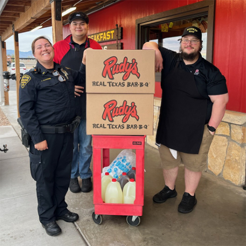 Smiling ODS members in uniform stand outside with Rudy's boxes.