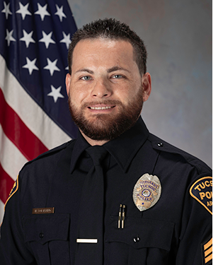 Department photo of TPD officer in uniform in front of an American flag.